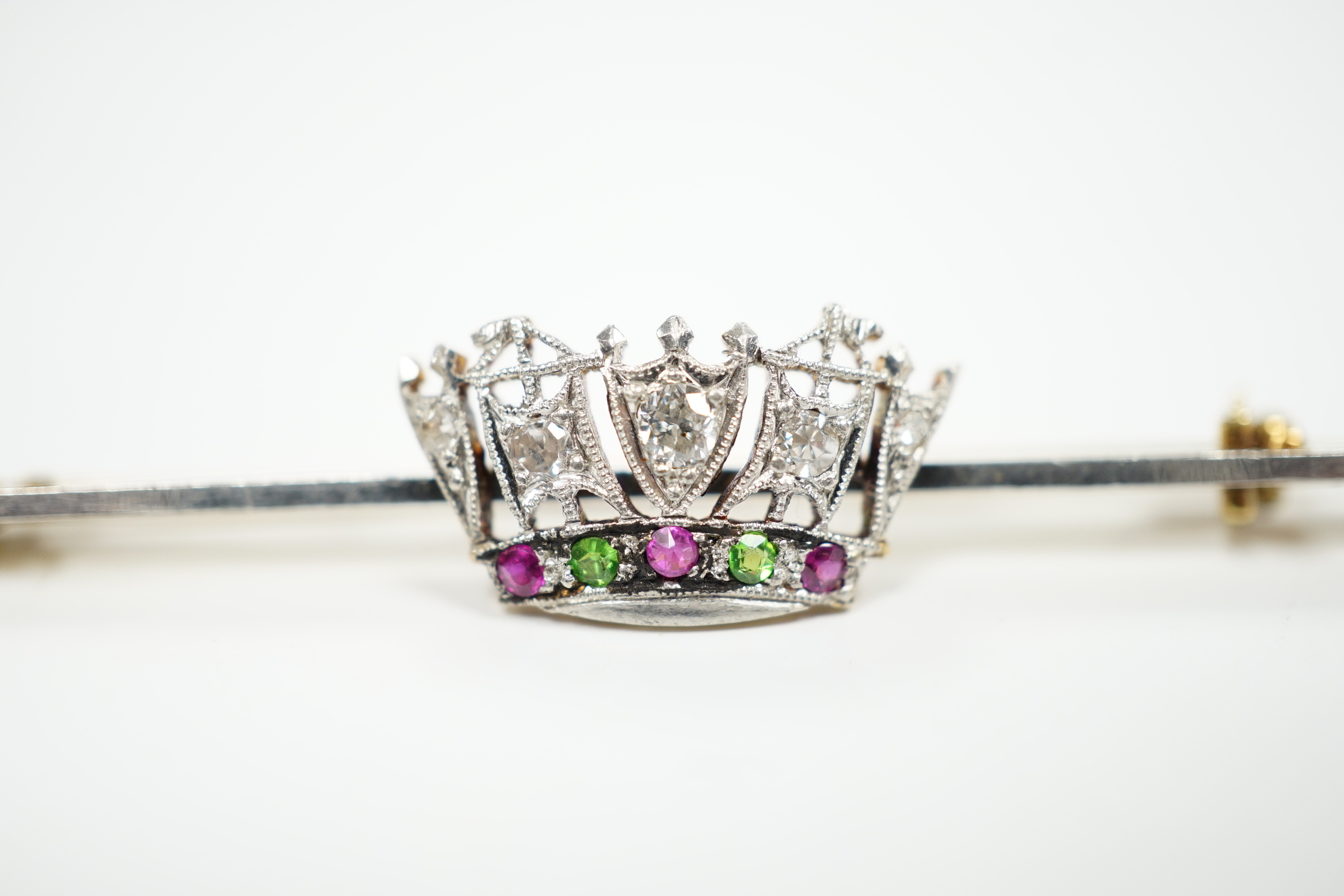 An early 20th century, 15ct and plat. ruby, green garnet and diamond set coronet bar brooch, 50mm, gross weight 3.4 grams.